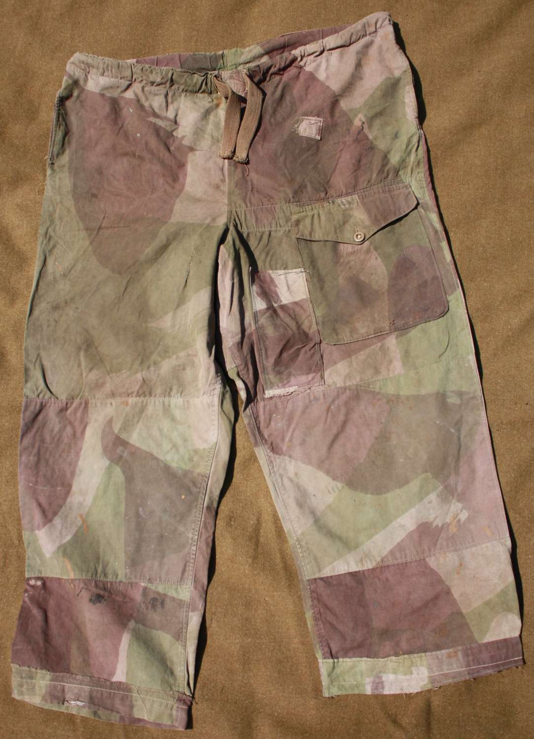 A WELL USED PAIR OF LARGE SIZE CAMOFLAGE WINDPROOF TROUSERS